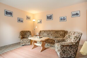 Ein Wohnzimmer mit floralen Sofas, einem kleinen Holztisch und einer Stehlampe.