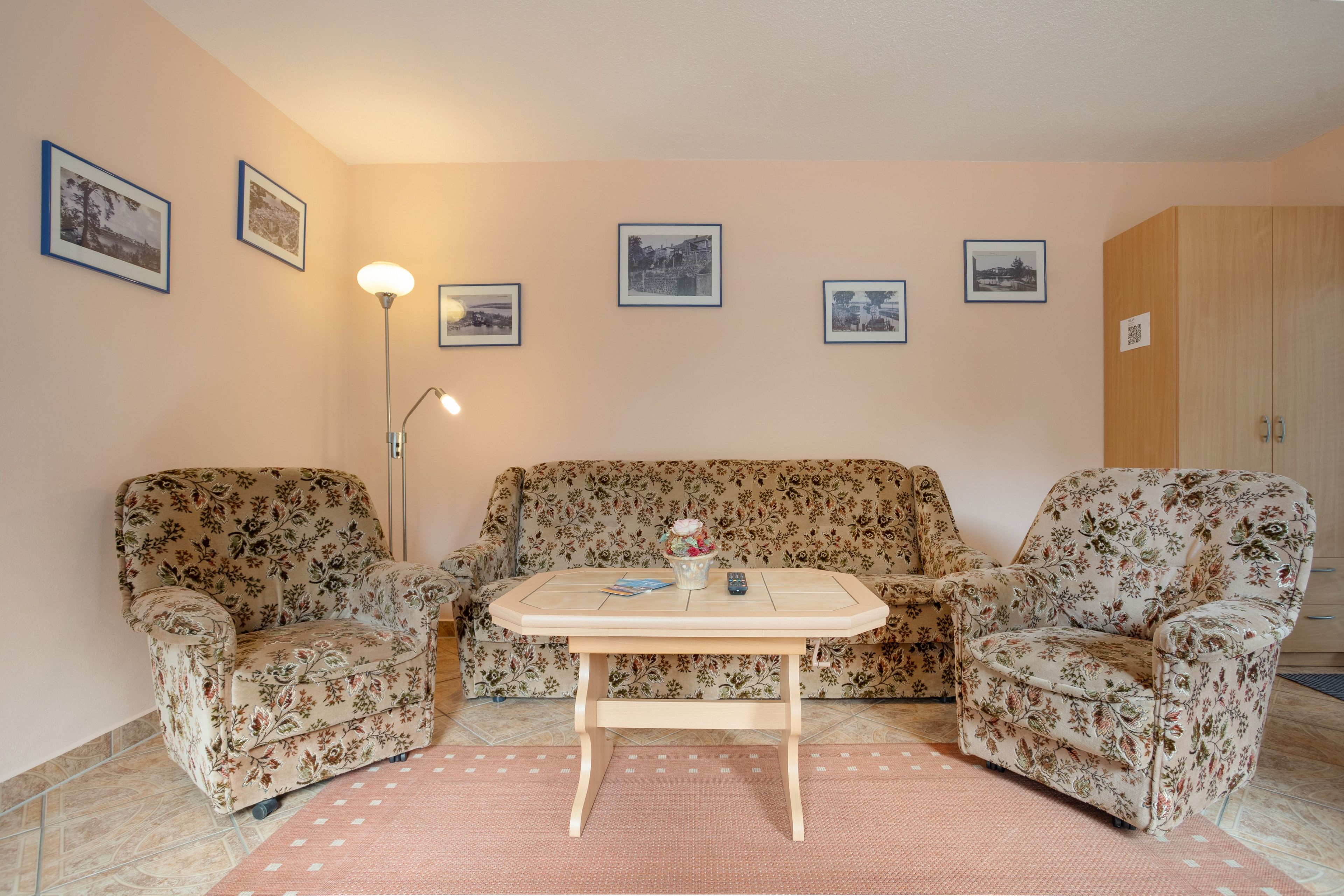 A living room with a floral sofa set, a small coffee table, and a floor lamp.