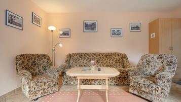 A living room with a floral sofa set, a small coffee table, and a floor lamp.