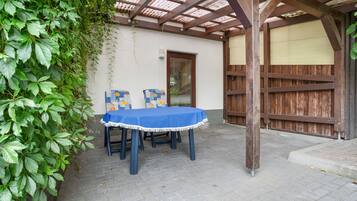 Eine Terrasse im Freien mit Tisch und Stühlen, einer Holzwolyleiter und einer Mauer mit einer Tür.