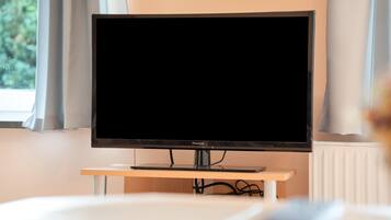Ein Fernseher auf einem Schrank in einem Zimmer mit Fenster und Vorhängen.