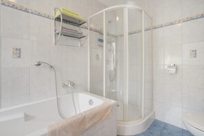 A bathroom with a bathtub, a glass-enclosed shower, and a toilet.