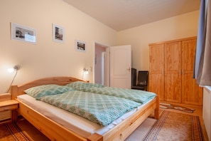 Une chambre à coucher avec un lit en bois, une table de chevet, une armoire et trois tableaux encadrés accrochés au mur.
