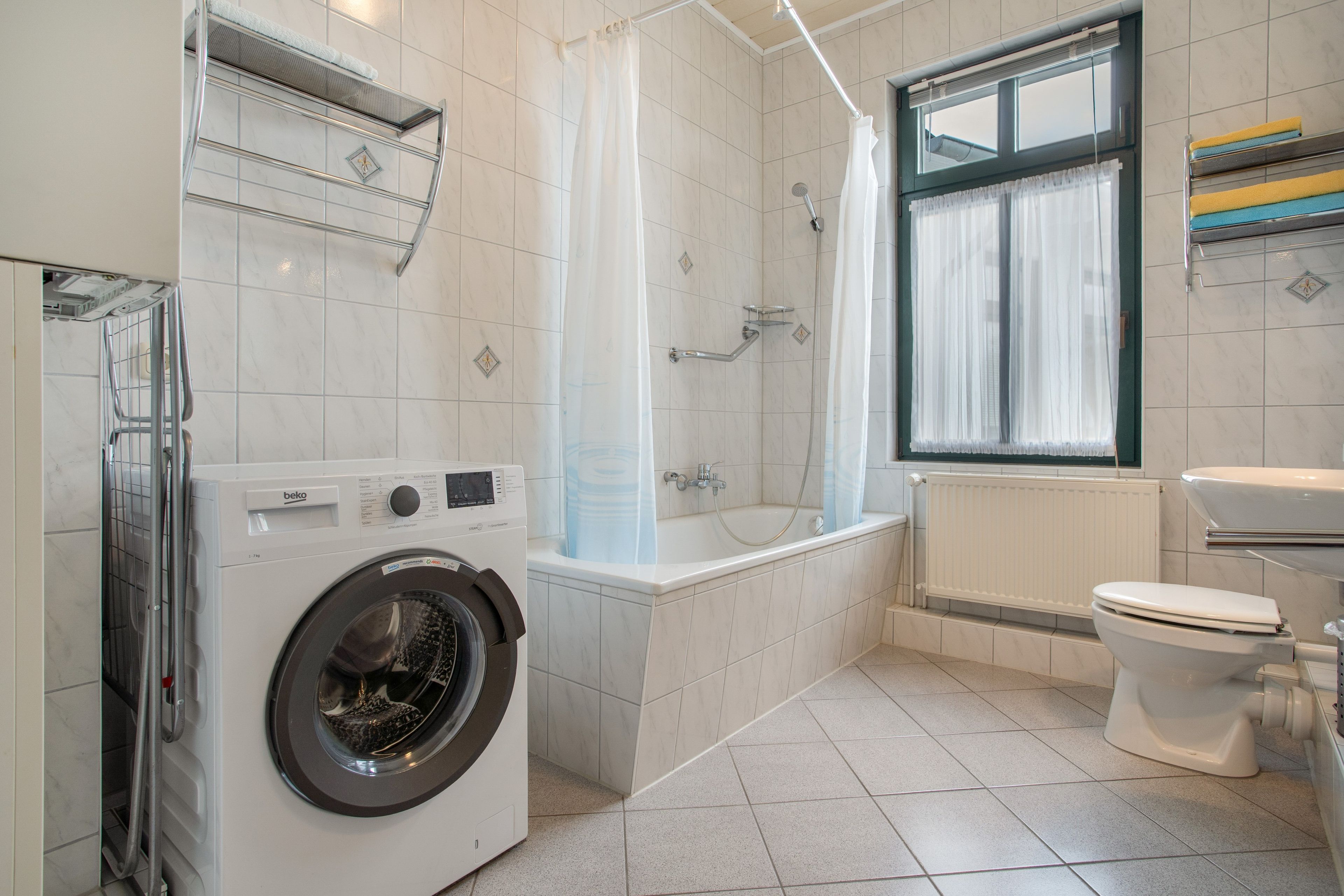 Ein modernes Badezimmer mit Waschmaschine, Badewanne und Toilette.