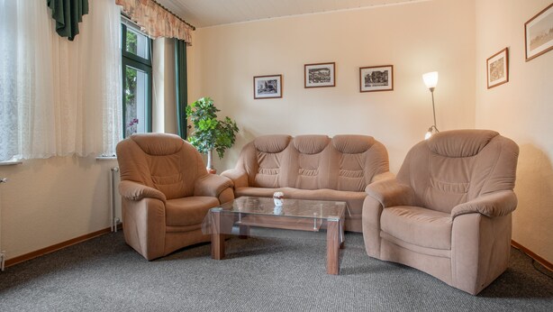 Ein Wohnzimmer mit einer Sofagarnitur, einem Couchtisch und einer Topfpflanze.