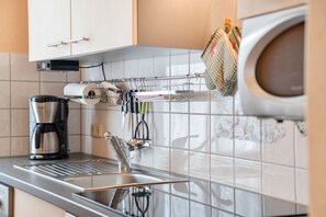 Une cuisine moderne dotée d’un évier en acier inoxydable, d’une machine à café et d’un étendoir suspendu pour les ustensiles de cuisine.