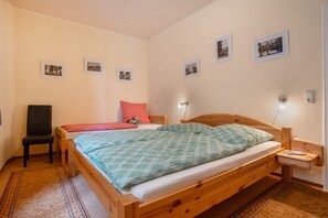 Une chambre avec deux lits, une chaise et une table de chevet avec une lampe.