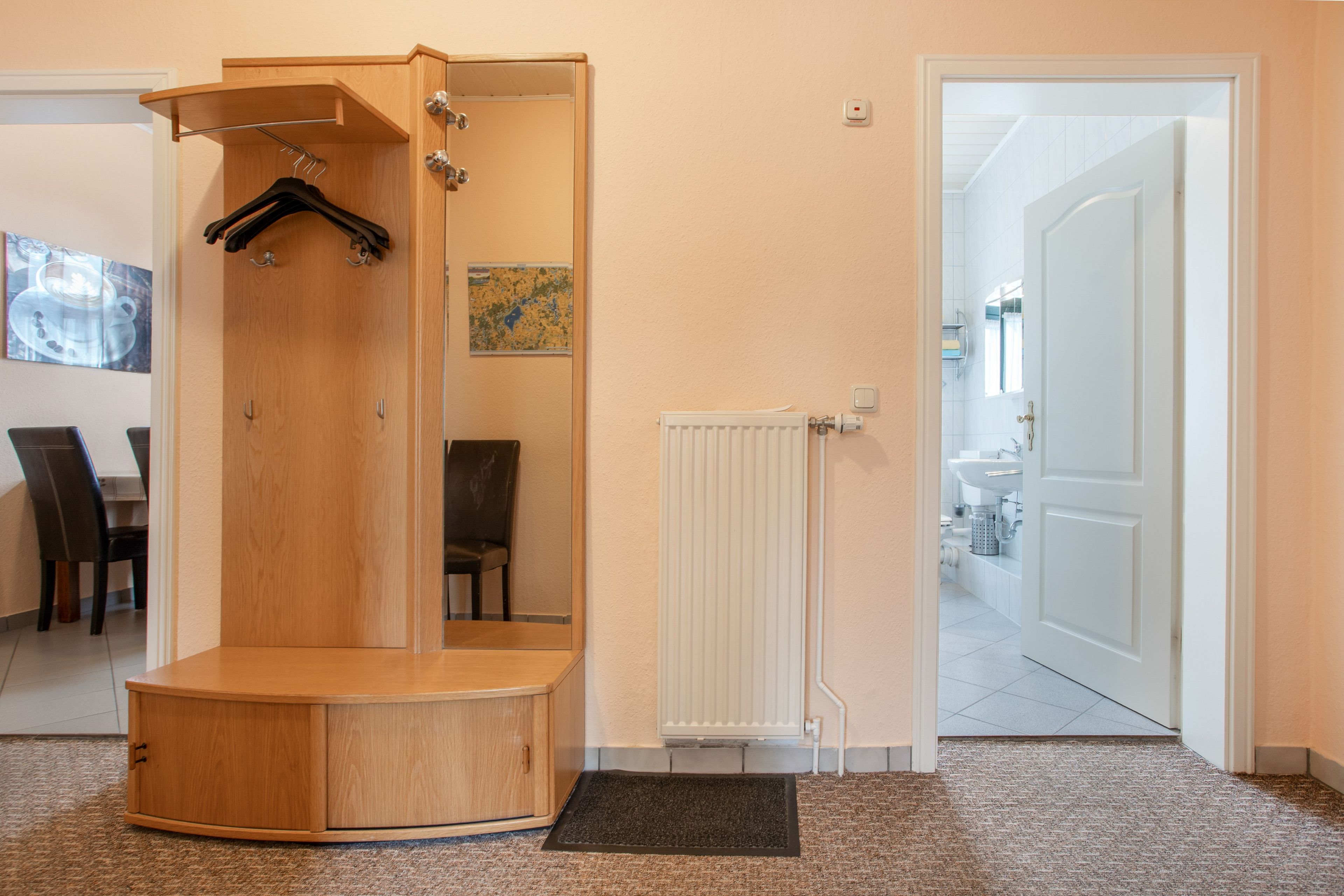 A room with a wooden shower enclosure, a radiator, and a door leading to a bathroom.
