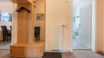A room with a wooden shower enclosure, a radiator, and a door leading to a bathroom.