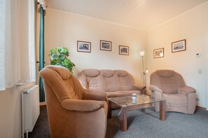 Ein gemütliches Zimmer mit zwei Sesseln, einem Couchtisch und einer Pflanze.