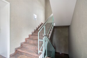 Eine Treppe mit Metallgeländer, Teppichstufen und einer schlichten Wand.