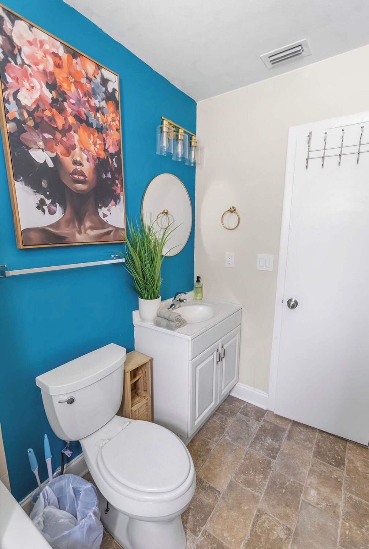 Ein Badezimmer mit Toilette, Waschbecken und Spiegel, einer blauen Wand und einer Tür mit Handtuchhalter.