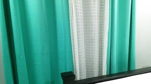 Een badkamer met blauwgroene gordijnen, een witte douchegordijn en een zwarte badrand.