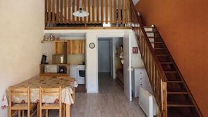 A compact kitchen with a dining table, wooden chairs, a microwave, and a stove. - Mountain views and comfort near Barcelonnette (Enchastrayes)