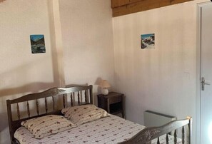 A bedroom with a wooden bed, a bedside table with a lamp, and two small wall-mounted pictures. - Mountain views and comfort near Barcelonnette (Enchastrayes)