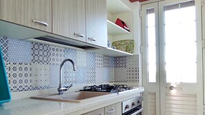 Una cocina con armarios de madera, una estufa a gas, un lavamanos y una ventana.