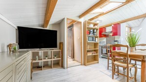 Una cocina moderna con armarios de madera, un comedor con una mesa y sillas de madera, y un televisor montado en la pared.