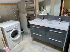 Een moderne badkamer met een wasmachine, een wastafel en een spiegel.
