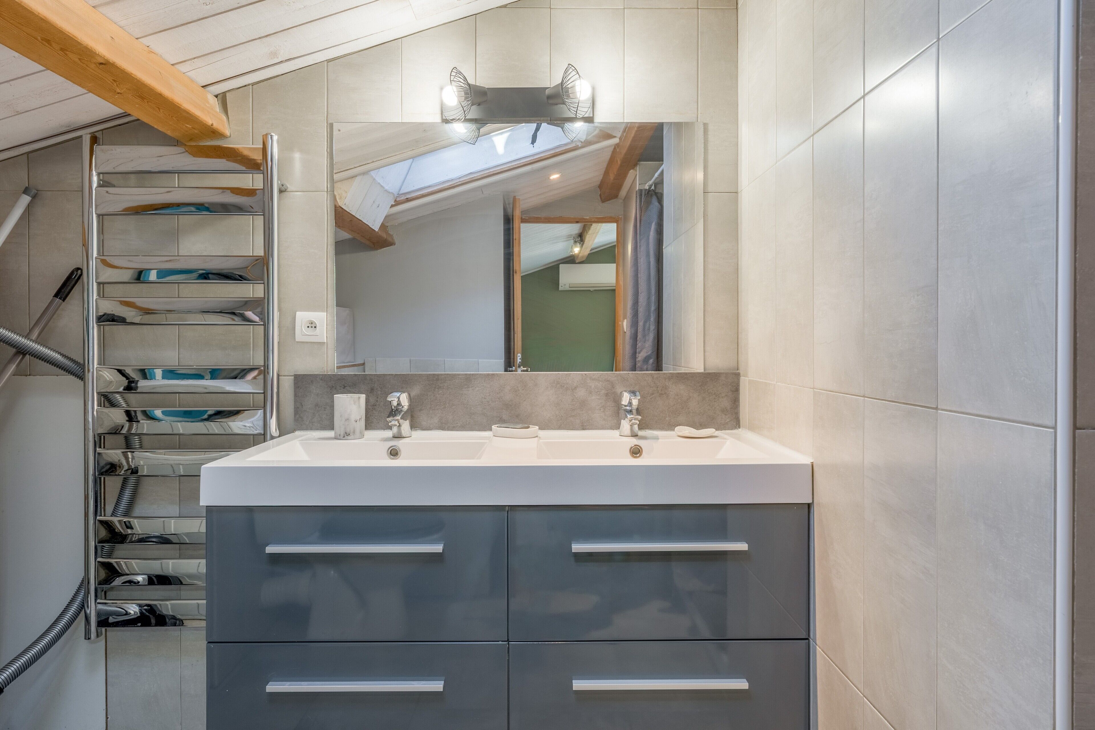 A modern bathroom with a double sink, a large mirror, and a built-in towel rack.