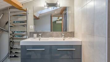 A modern bathroom with a double sink, a large mirror, and a built-in towel rack.
