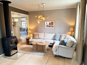 A cozy living room with a sofa, coffee table, and a fireplace. - Rural charm and modern comfort – close to nature and swimming |SE08016 (Ljung)