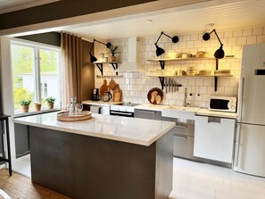 Una cucina moderna con isola centrale, mobili bianchi, un forno a microonde e un frigorifero.