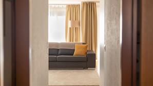 A hallway leading to a living room with a sofa and a lamp.