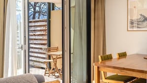 A room with a wooden table and chairs, a sliding glass door leading to an outdoor area with a wooden deck and chairs.