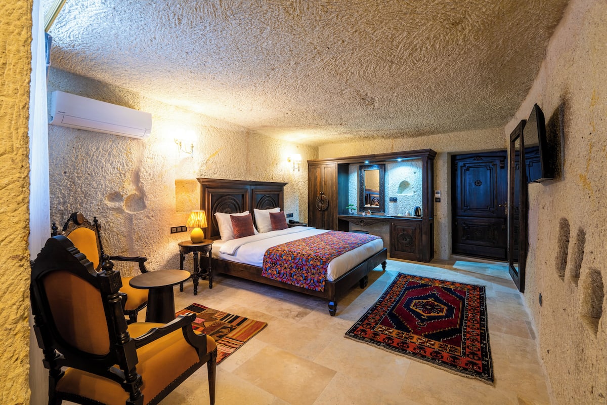 Um quarto com uma cama, uma cadeira, uma mesa, um abajur e um tapete.