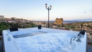 A hot tub with a view of a rocky landscape and buildings. - Aurelia Cave Cappadocia (Urgup)