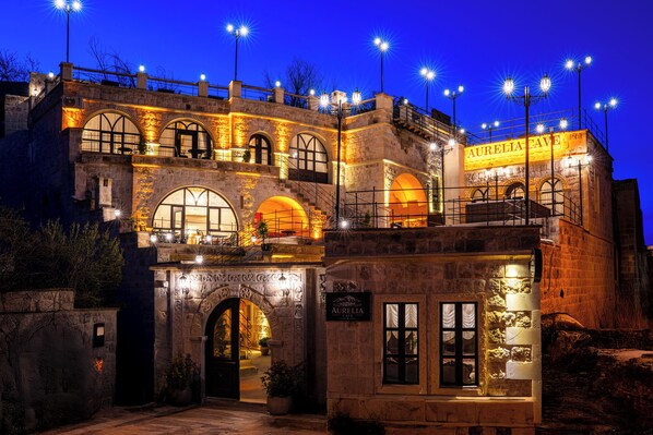 Un edificio de piedra con un letrero que dice 'Aurelia Cave' y varios ventanales de arco.