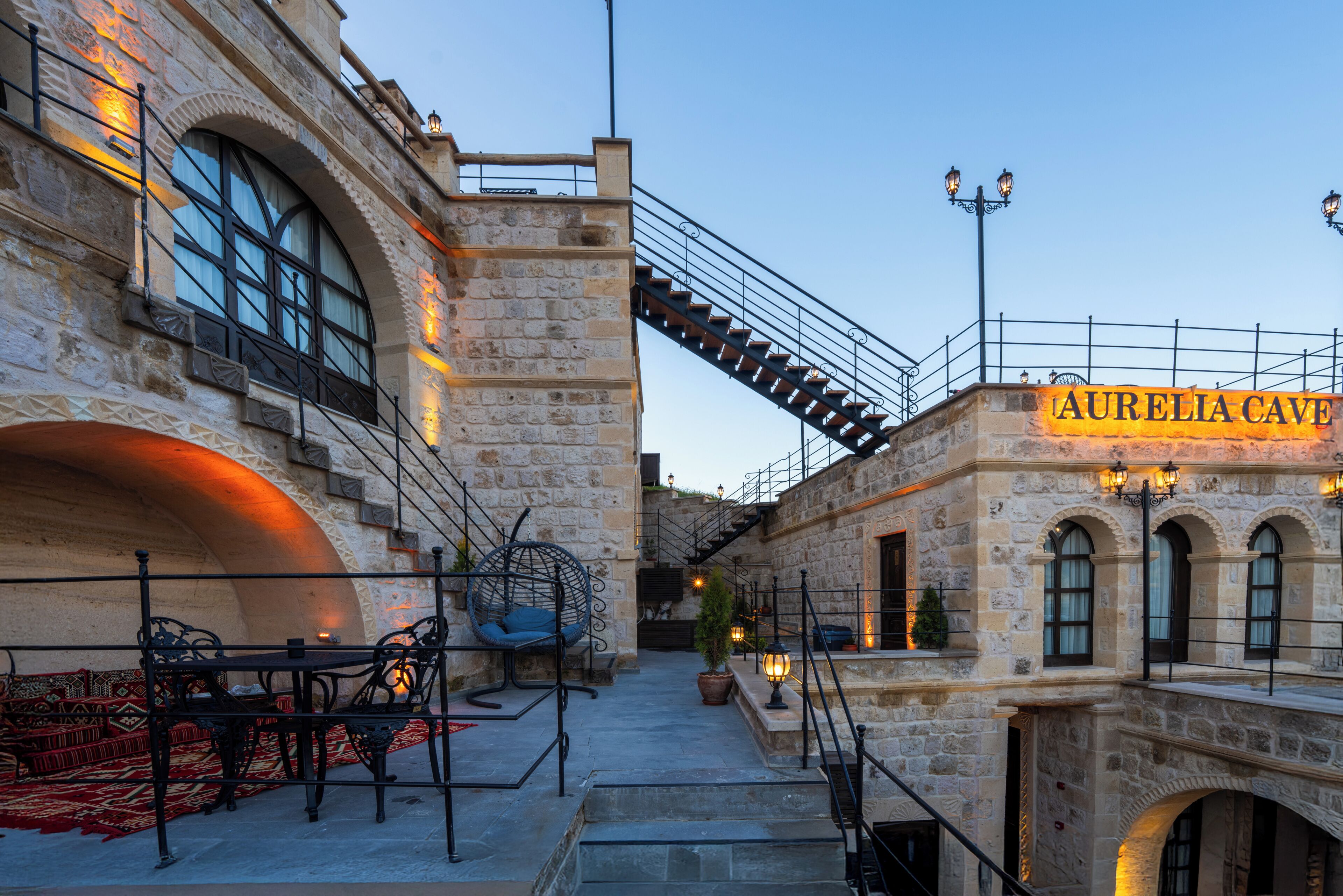 Un bâtiment en pierre avec une enseigne indiquant « Grotte d’Aurélia », des places assises à l’extérieur et un escalier.