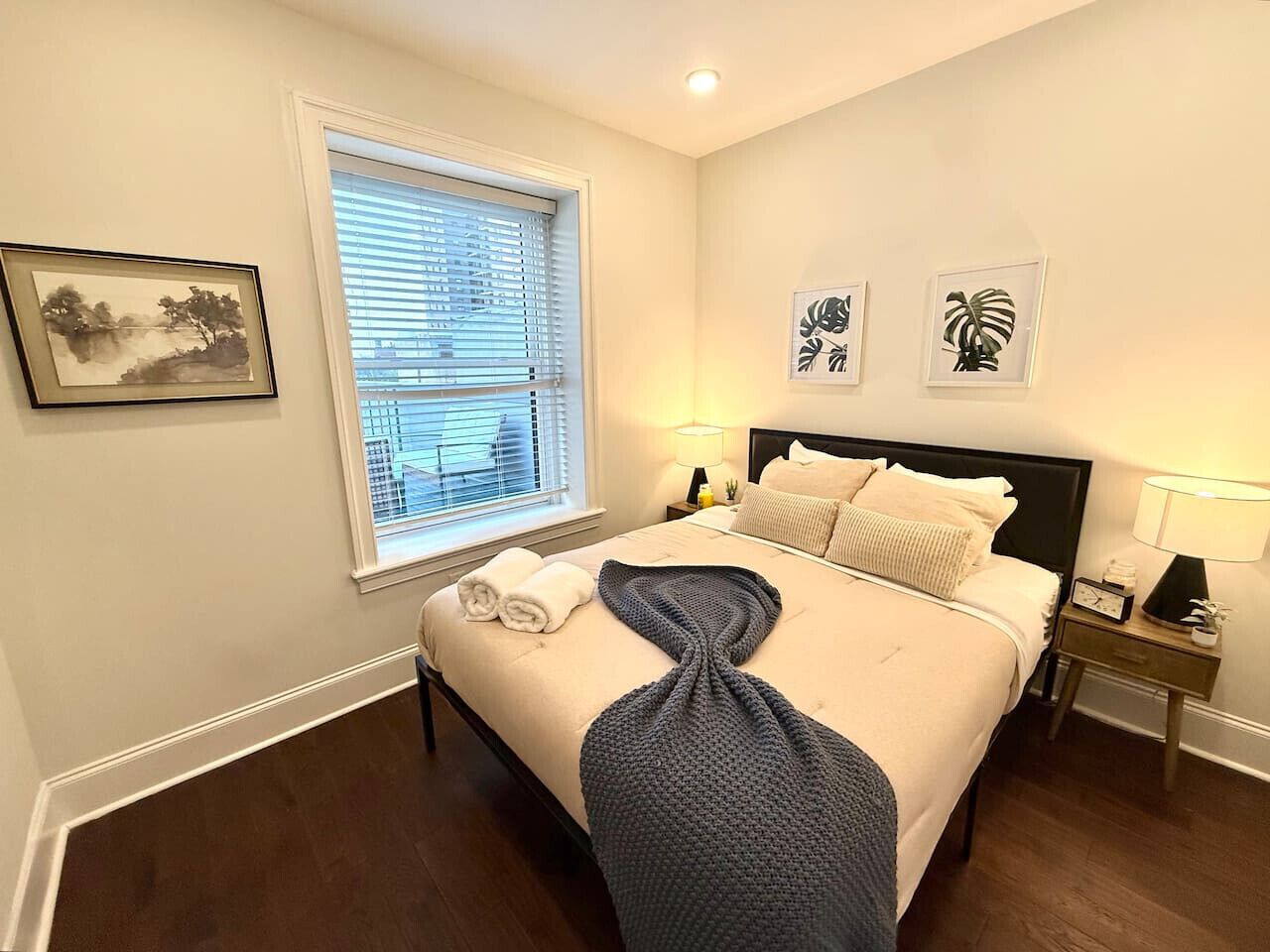 A neatly made bed with a towel, a bedside lamp, and a framed picture on the wall.