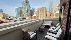 A rooftop terrace with outdoor seating, a city skyline view, and a brick wall. - Spacious Center City 2BR 2Bath Apt. with Balcony (Philadelphia)