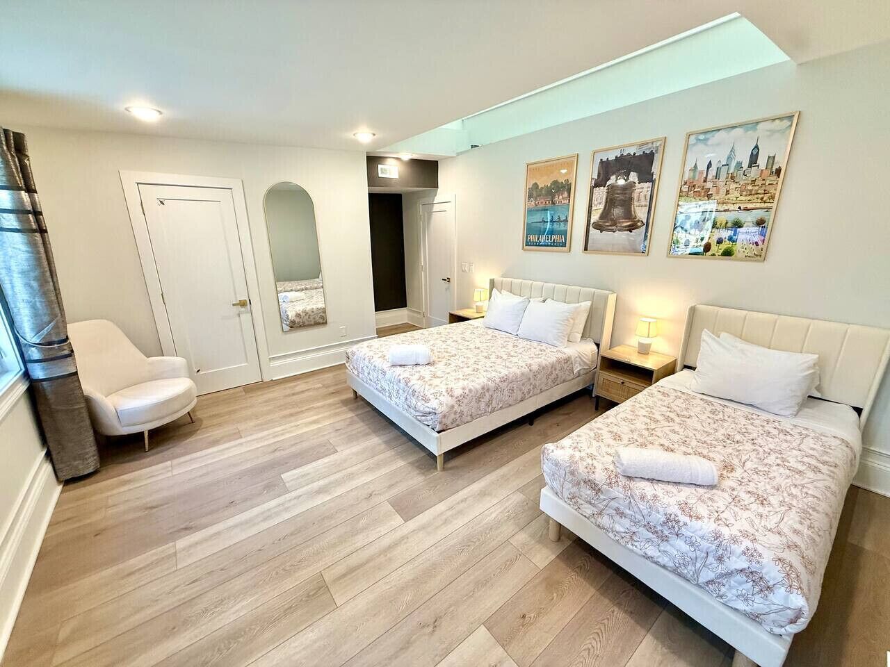A hotel room with two beds, a chair, a door, and a wall with pictures.
