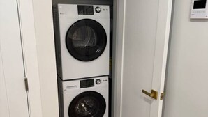 Ett tvättrum med två staplade tvättmaskiner och en dörr.