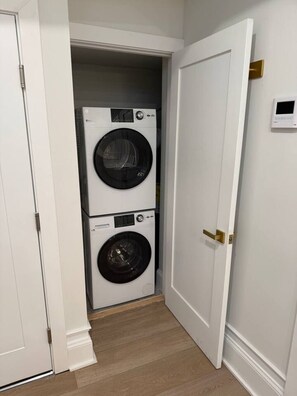 A laundry room with two stacked washing machines and a door. - Grand Luxury Center City 2BR & 2Bath Apartment (Philadelphia)