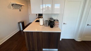 A modern kitchen with a central island, white cabinets, and a stainless steel trash can. - Private Balcony | Gorgeous Center City Bilevel Apt (Philadelphia)