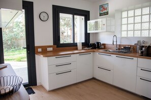 Een moderne keuken met witte kasten, een houten aanrecht, een ingebouwde spoelbak en een klok aan de muur.