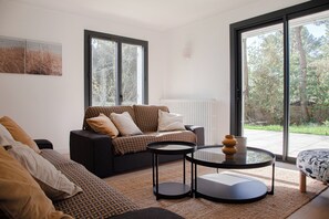 A modern living room with a sofa, a coffee table, and a view of the outdoors.
