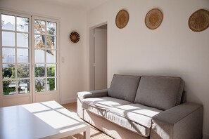 Een kamer met een bank, een tafel en uitzicht door een raam.