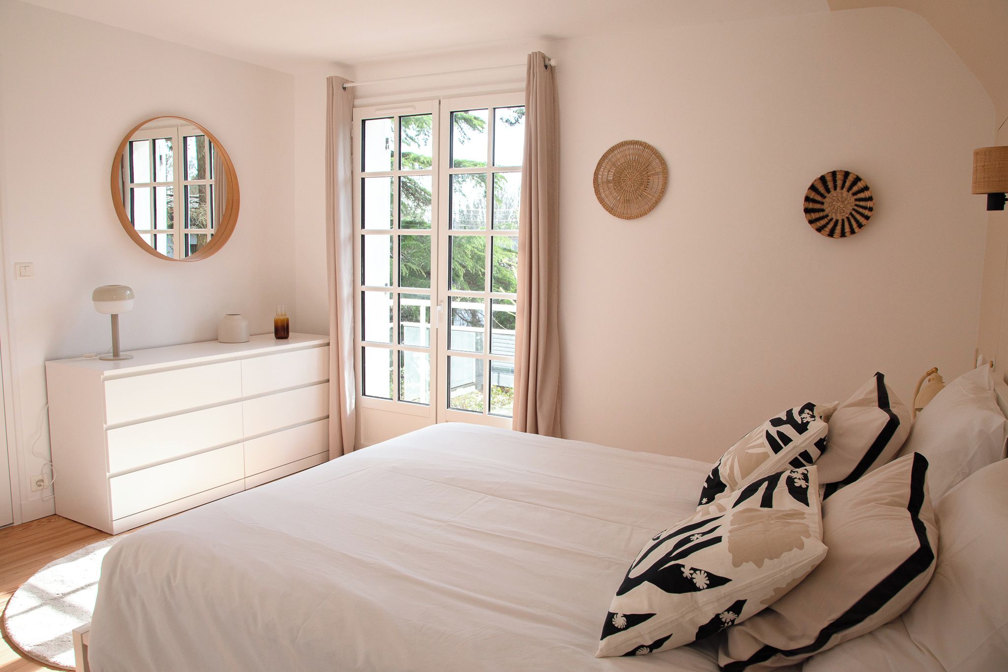 Ein Schlafzimmer mit einem Bett, einem Schminktisch, einem Spiegel und einem Fenster mit Vorhängen.