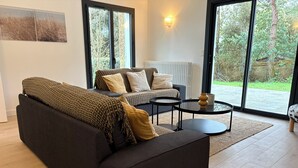A modern living room with a dark brown sofa, a patterned sofa, and a round coffee table. - Premium villa, enclosed garden, games room. (La Baule-Escoublac)