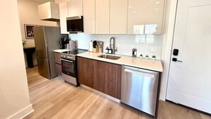 Une cuisine moderne dotée d’appareils électroménagers en acier inoxydable, de meubles en bois et d’un lave-vaisselle encastré.