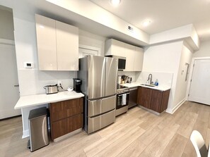 Eine moderne Küche mit Edelstahlgeräten, Holzschränken und einer weißen Arbeitsplatte.