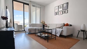 A modern living room with a sofa, coffee table, and a view through large windows. - Marinsa Gaviota (Torrox)
