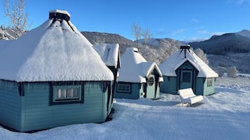 A row of snow-covered houses with a clear sky and mountains in the background.