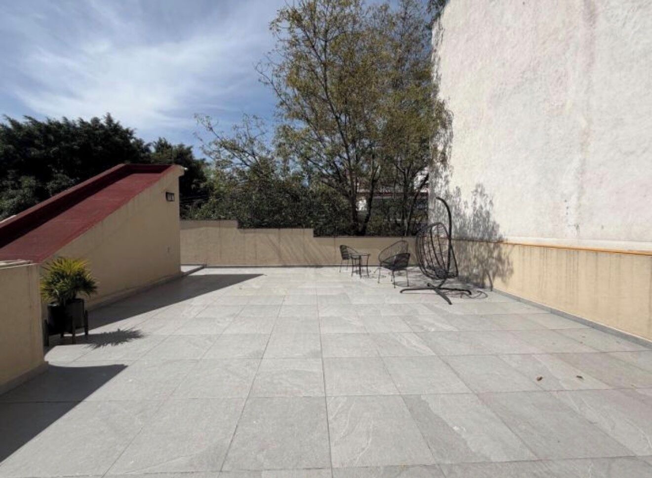 Une terrasse sur le toit, dotée d’un sol carrelé, d’un toit rouge et de mobilier d’extérieur.