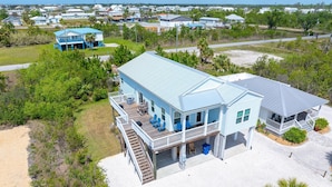 A coastal house with a deck, a covered porch, and a staircase leading to the main floor. - Rhapsody in Blues (Port St. Joe)