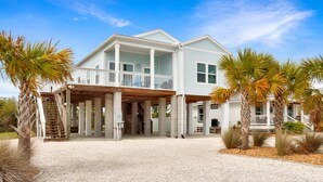 A two-story house with a covered porch, a staircase, and palm trees. - Rhapsody in Blues (Port St. Joe)